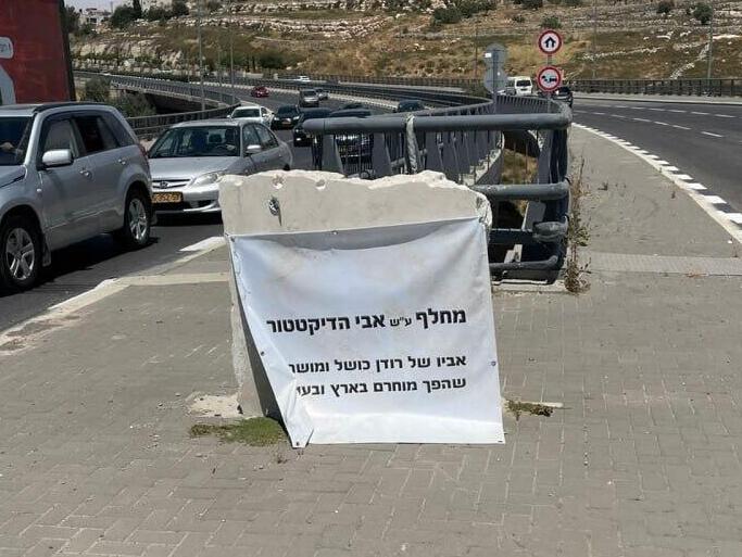 Плакат, закрывший памятный знак на развязке в Иерусалиме השלטים שנתלו במחלף בן ציון נתניהו, ע"ש אביו של בנימין נתניהו