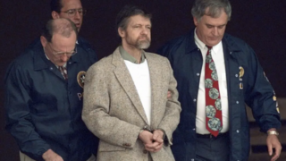 Theodore Kaczynski looks around as U.S. Marshals prepare to take him down the steps at the federal courthouse to a waiting vehicle on June 21, 1996, in Helena, Mont. 