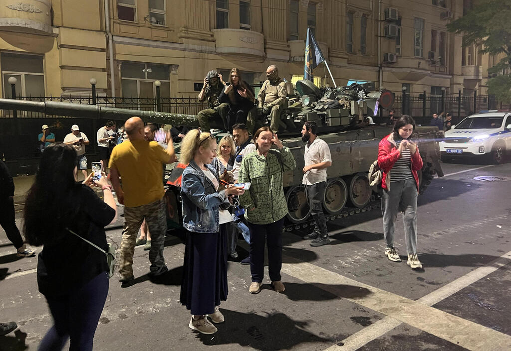 אנשים מתאספים ליד לוחמי קבוצת שכירי החרב הפרטית של וגנר ברחוב ליד מפקדת המחוז הצבאי הדרומי בעיר רוסטוב-על-דון, רוסיה