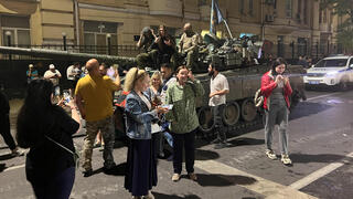 אנשים מתאספים ליד לוחמי קבוצת שכירי החרב הפרטית של וגנר ברחוב ליד מפקדת המחוז הצבאי הדרומי בעיר רוסטוב-על-דון, רוסיה