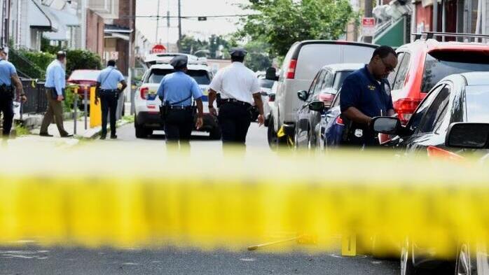 Police officers work at the scene as investigations are ongoing the day after a mass shooting in the Kingsessing section of southwest Philadelphia, Pennsylvania 