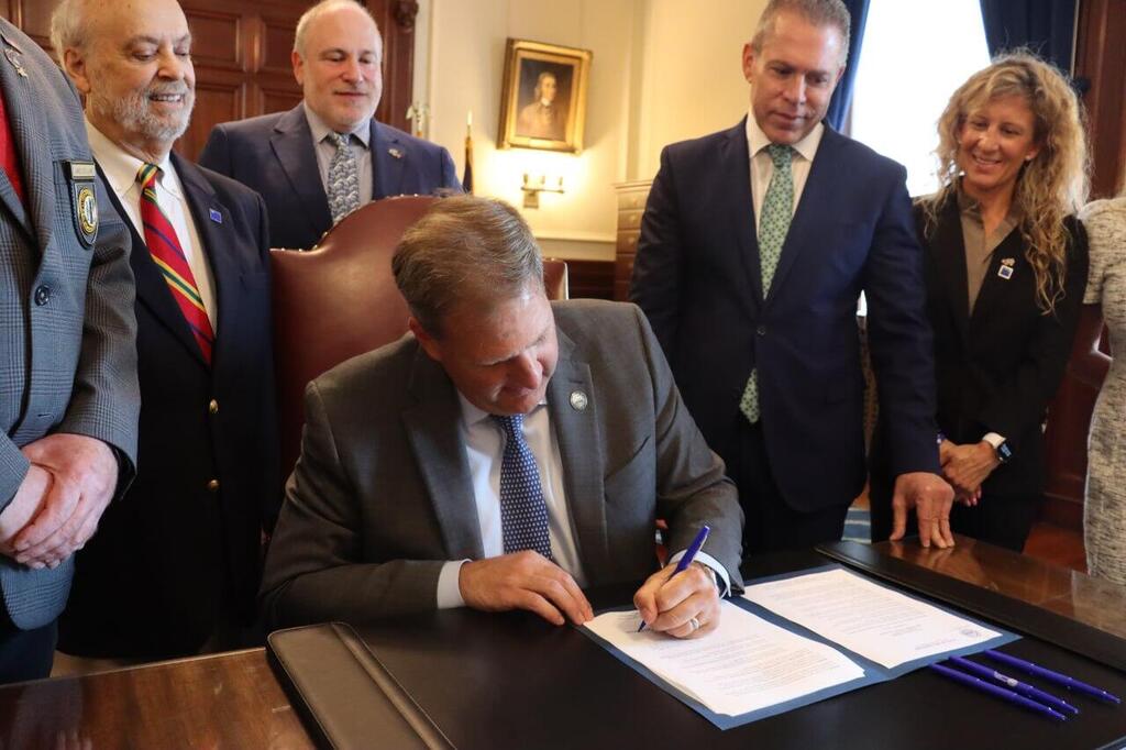 NH Gov. Christopher Sununu signs an executive order against the anti-Israel BDS movement; Looking on to his immediate right is Israel’s Permanent Representative to the United Nations, Ambassador Gilad Erdan 