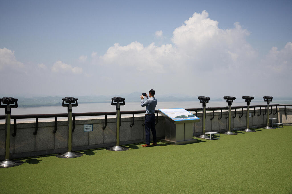 דרום קוריאה תייר מצלם את שטח צפון קוריאה מ עמדת תצפית ב האזור המפורז