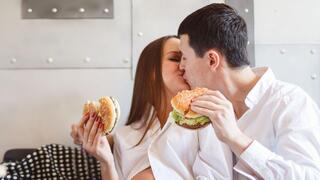 אישה בהיריון וגבר אוכלים המבורגר