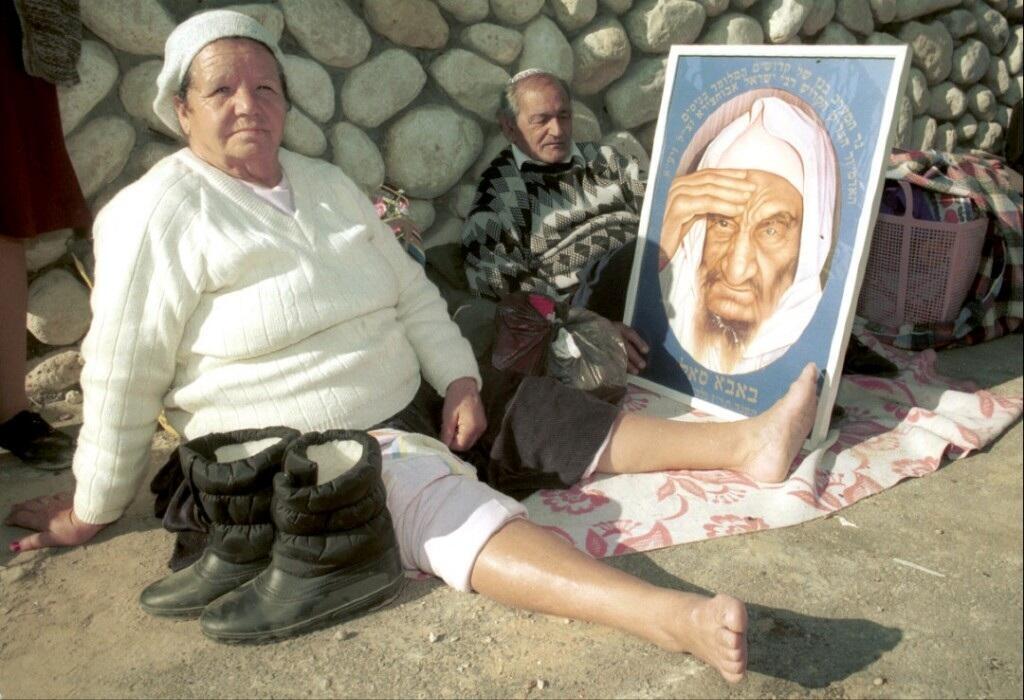 A Moroccan origin sitting near the Baba Sali tomb at Netivot, Israel holding a portrait of the late Rabbi Baba Sali, 1990 
