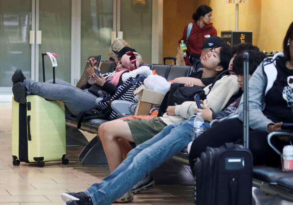 People sit at San Diego International Airport area as Tropical Storm Hilary approaches