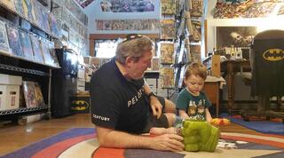 Rabbi Victor Urecki plays with his grandson in his comic book room.