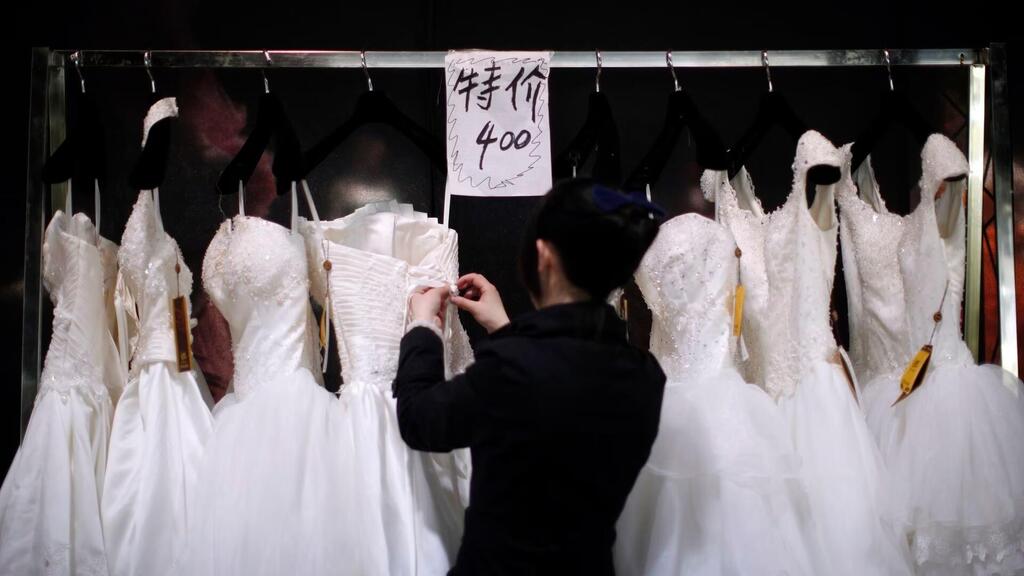 A vendor prepares wedding dresses at a show room during the China International Wedding Expo in Shanghai 