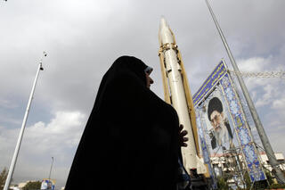 Iranian woman walks next to the Sejil surface-to-surface missile displayed at a street exhibition on the occasion of 'Defence Week' in Tehran 