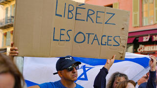 מפגין אוחז בכרזה "שחררו את בני הערובה" במהלך עצרת תמיכה בישראל בעיר ניס בריביירה הצרפתית