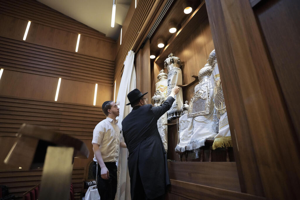 Rabbi Yehuda Teichtal, right, prepares Torah scrolls at the synagogue of the Chabad community prior to the first Shabbat service after the Hamas attacks on Israel