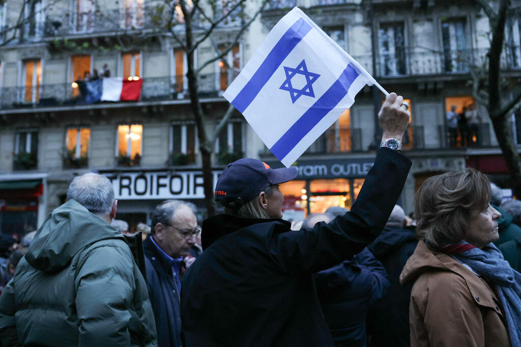 פריז, צרפת אישה מרימה דגל ישראל במהלך צעדה נגד האנטישמיות חרבות ברזל