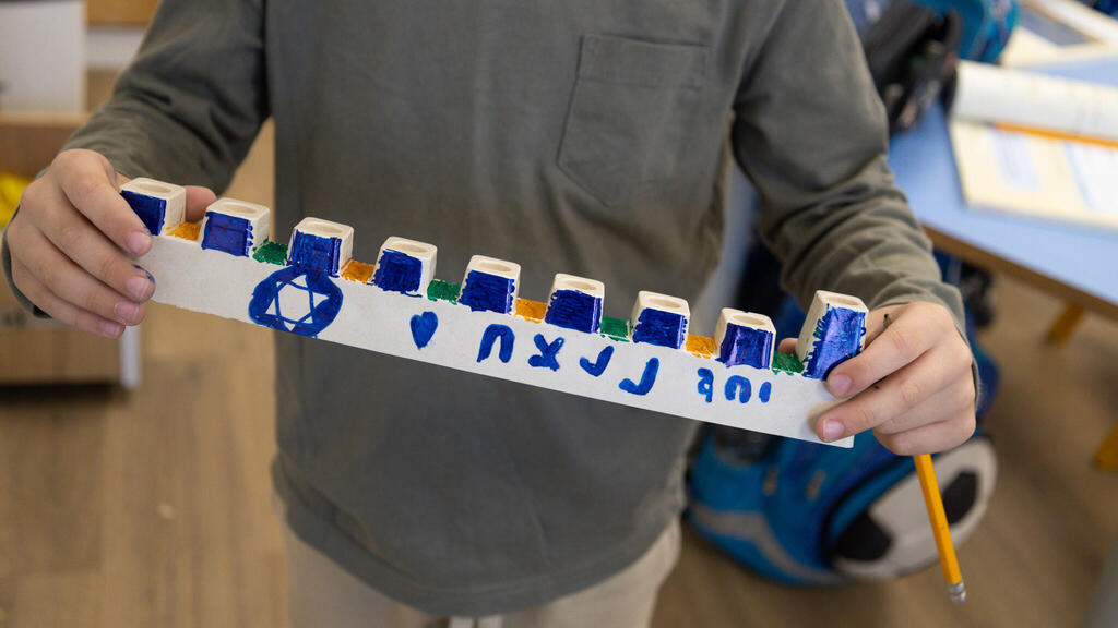 לוחמי צה"ל מדליקים נרות בתוך שטח רצועות עזה, עם חנוכיות שקושטו על ידי חברי הקהילות המפונות