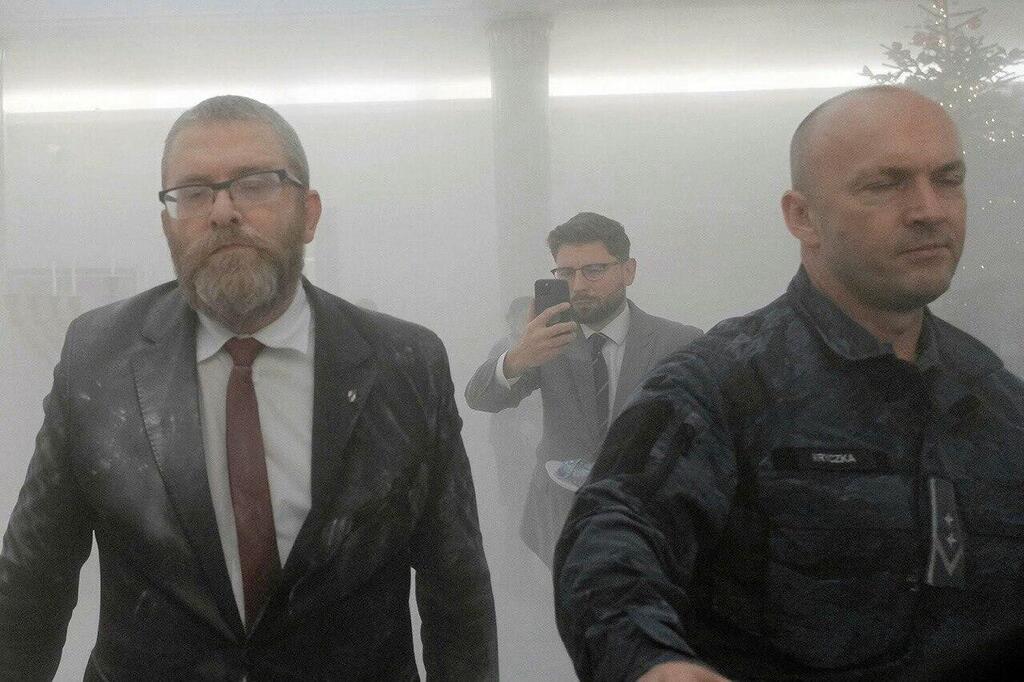 Far-right Polish lawmaker Grzegorz Braun is led away after he used a fire extinguisher to put out Hanukkah candles lit in Poland's Parliament