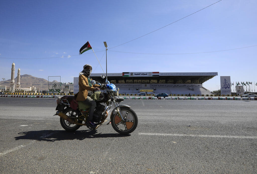 A person rides a motorcycle with a Palestinian flag waving through a square in Sana'a, Yemen