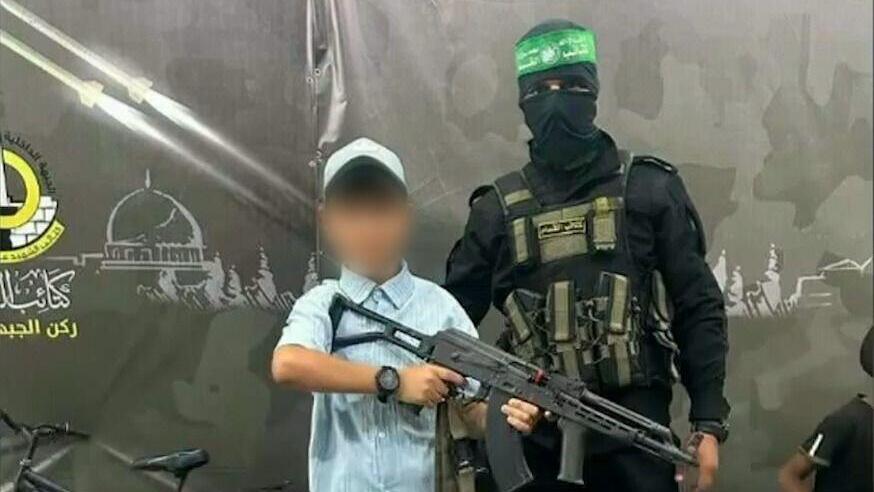 A Gazan child holding a rifle next to a Hamas terrorist (Photo: IDF Spokesperson's Unit) תיעוד: חמאס והג׳יהאד האיסלמי משתמשים בילדים לפעילות צבאית והסתה מגיל צעיר