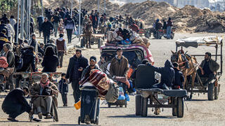 פליטים פלסטינים מתפנים מ חאן יונס כשברקע נראה דחפור של צה"ל ב רצועת עזה