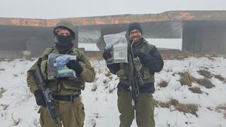 Soldiers stationed on Mt. Hermon holding essential items supplied by Vaad Hatzedaka volunteers 