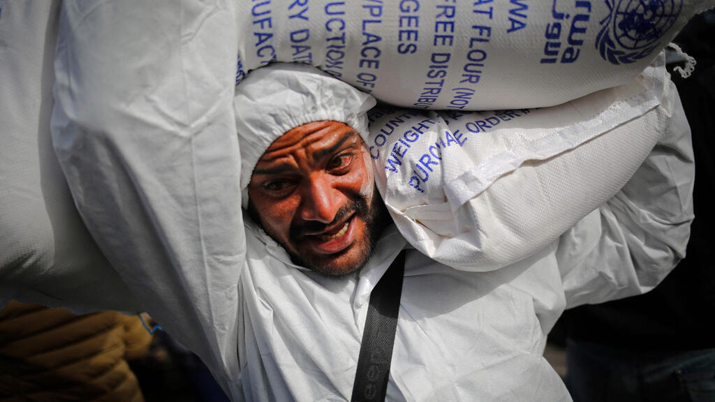 Gazan carries sacks of flour delivered in Rafah (Photo: AFP) חלוקת שקי שק קמח של אונר"א ל פליטים ב רפיח רצועת עזה