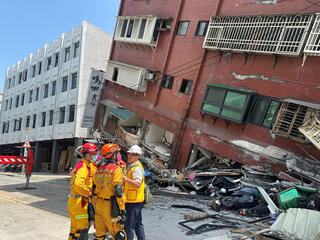 Firefighters work at the site where a building collapsed following the earthquake 