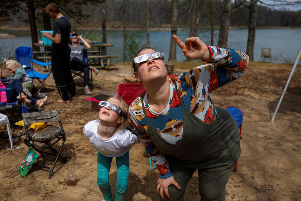 Brittany Sunderman and Gianna Debenham, 6, and other members of the Debenham family who travelled from Utah and Las Vegas to experience the total solar eclipse together, try out their eclipse viewing glasses at their campsite a day ahead of the event at Camp Carew in Makanda, Illinois.