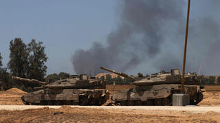 טנקים של צה"ל בדרום ישראל כשברקע עשן בצל תקיפות ברצועת עזה והמבצע ב רפיח