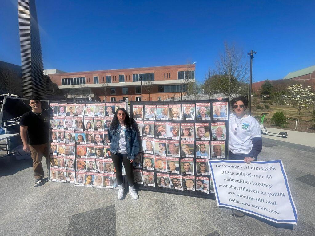 Kahn and her friends in front of a banner calling for the return of the hostages (Photo: Ethan Povlot) קהן וחבריה לצד שלטים למען החטופים, לאחר 7 באוקטובר