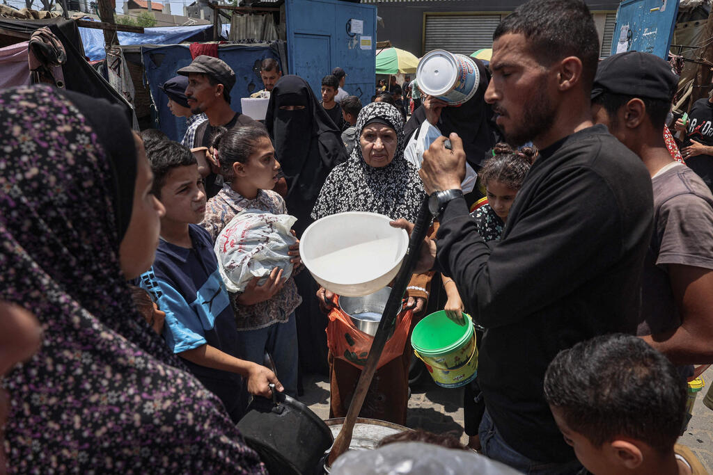 Palestinian line up for food distribution in Bureij, central Gaza (Photo: Eyad BABA / AFP) חלוקת מזון ב מחנה הפליטים אל-בוריג'