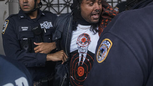 מפגין לובש את החולצה של Comrade Workwear בהפגנה נגד ישראל בניו יורק, מאי 2024