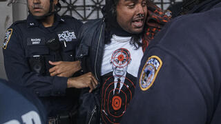 מפגין לובש את החולצה של Comrade Workwear בהפגנה נגד ישראל בניו יורק, מאי 2024