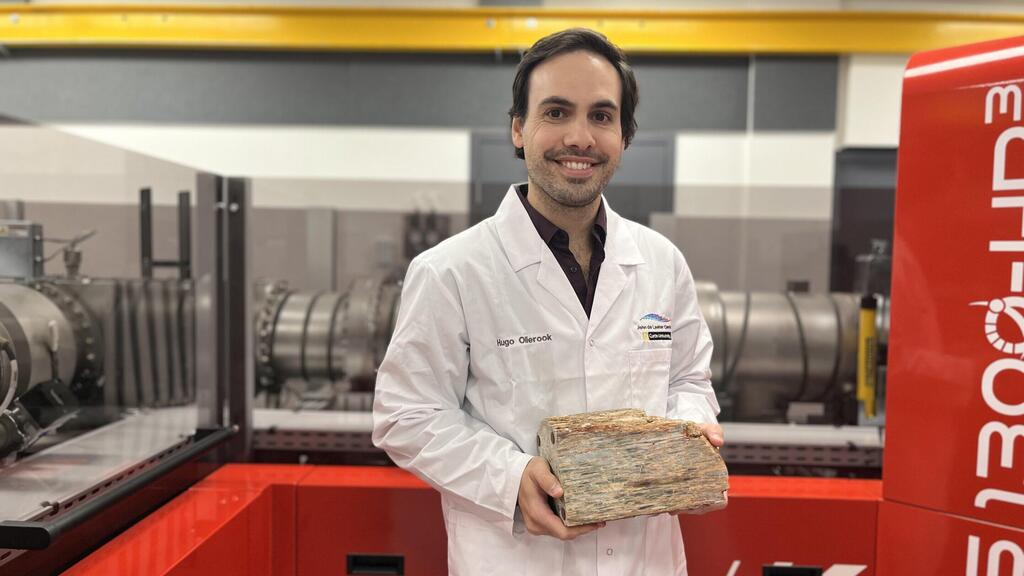 ד"ר הוגו אולירוק מאוניברסיטת קרטין עם סלע מג'ק הילס שבאוסטרליה המערבית, שהכיל את גבישי הזירקון שנותחו על ידי צוות המחקר שהוא נמנה עליו