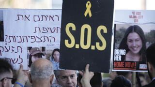 שלט מחאה בדרישה ל עסקה למען ה חטופים כשברקע ניתן לראות את פניו של מזכיר המדינה האמריקני אנתוני בלינקן שנועד עם קרובי חטופים מחוץ לשגרירות ארה"ב ב תל אביב