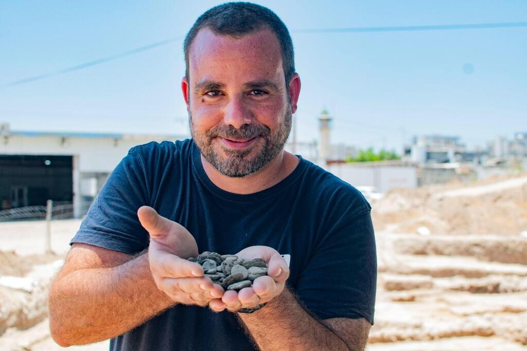 הארכיאולוג שחר קריספין מחזיק את מטמון המטבעות לאחר מציאתו