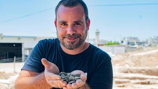 הארכיאולוג שחר קריספין מחזיק את מטמון המטבעות לאחר מציאתו