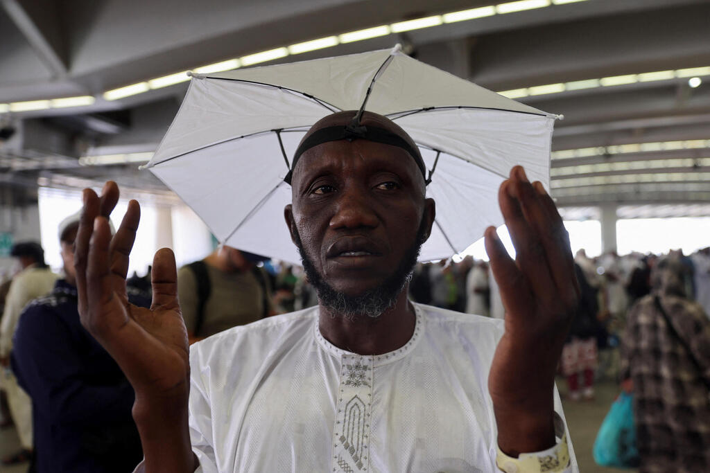 A Muslim pilgrim prays after casting a stone at a pillar symbolizing Satan, amidextremely hot weather, during the annual hajj pilgrimage in Saudi Arabia,