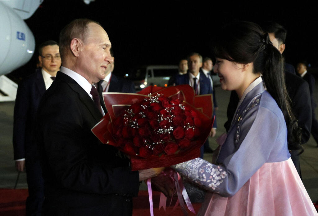 Russian President Vladimir Putin receives flowers during a welcoming ceremony upon arrival in Pyongyang 