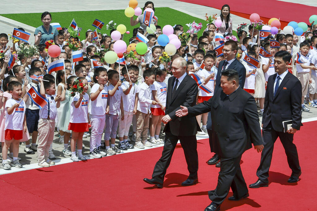 Russian and North Korean leaders walk past children gathered to greet them 