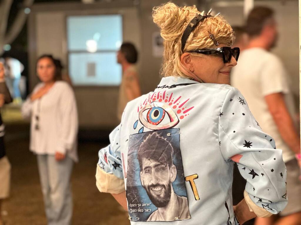 אורית שחף מלהקת היהודים עם תמונתו של גיא אילוז על הג'קט, במופע המחווה לנובה בפארק הירקון