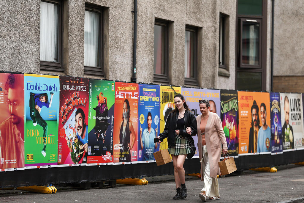 Members of the public walk past posters advertise shows at the Edinburgh Festival Fringe in Scotland, which runs through August 26.