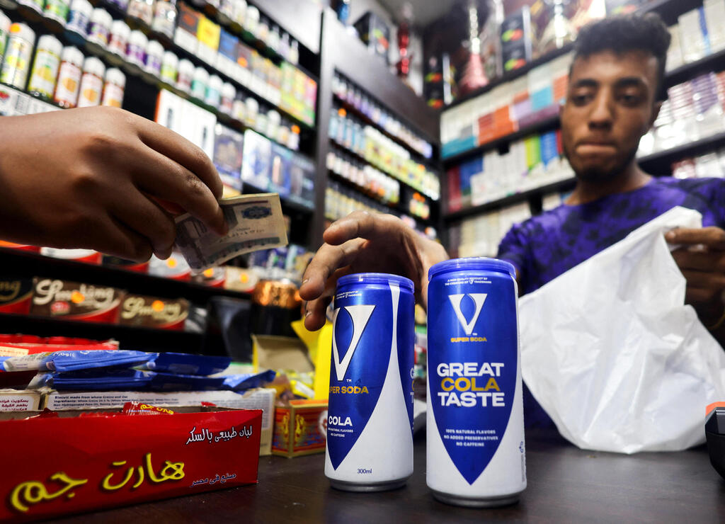 An Egyptian supermarket owner sells cans of soda beverage of a local brand V Super Soda Cola