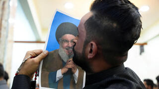 מתנדב עיראקי מנשק תמונה של נסראללה לאחר החיסול