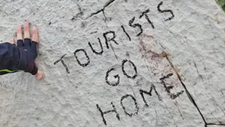 כתובת "תיירים לכו הביתה" על סלע בהרי הדולומיטים