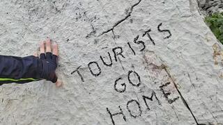 The vandalized stone with the writing "tourists go home" 