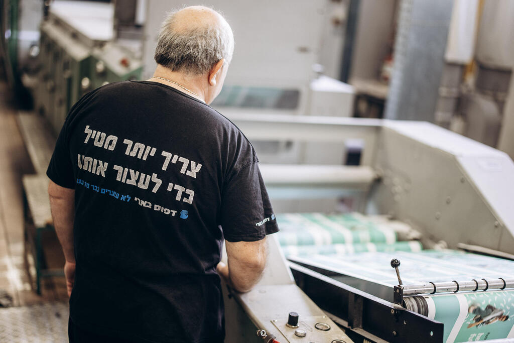 Be'eri printing house employee wearing a shirt that reads, 'you need more than a rocket to stop us' (Photo: Micha Brikman) בארי