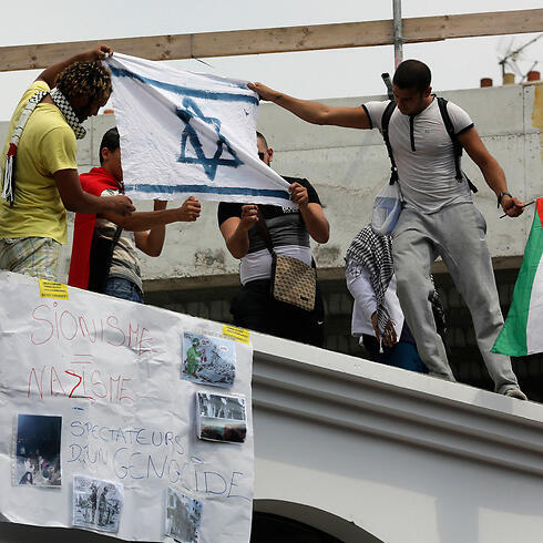Protesters set fire to an Israeli flag during a rally in Paris against Operation Protective Edge, July 2014. (Photo: AP)