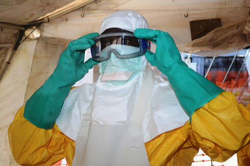 Israeli doctors will treat the patient in full protective gear according to protocol, like this health worker in west Africa. (Photo: AFP) (צילום: AFP ) Israeli doctors will treat the patient in full protective gear according to protocol, like this health worker in west Africa. (Photo: AFP)