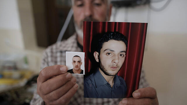 A relative of Uday and Rassan Abu Jamal holds their pictures (Photo: AFP)