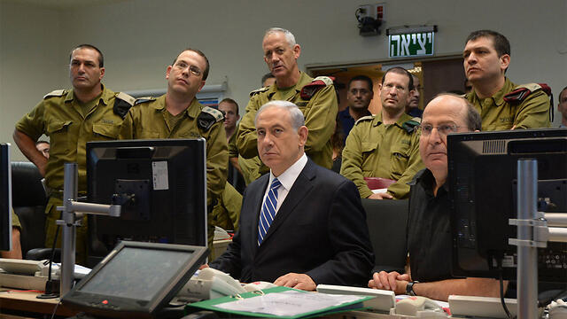 Then-IDF chief Gantz (standing in the middle), Prime Minister Netanyahu and then-defense minister Ya'alon (both seated) at the Kirya IDF headquarters during Operation Protective Edge (Photo: GPO) (צילום: חיים צח, לע"מ) Then-IDF chief Gantz (standing in the middle), Prime Minister Netanyahu and then-defense minister Ya'alon (both seated) at the Kirya IDF headquarters during Operation Protective Edge (Photo: GPO)