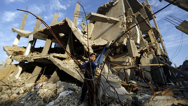 Palestinian boy playing outside building destroyed in summer Gaza war (Photo: AFP)