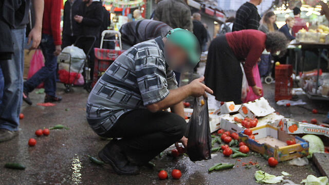 People collect food from ground in Carmel Market in Tel Aviv